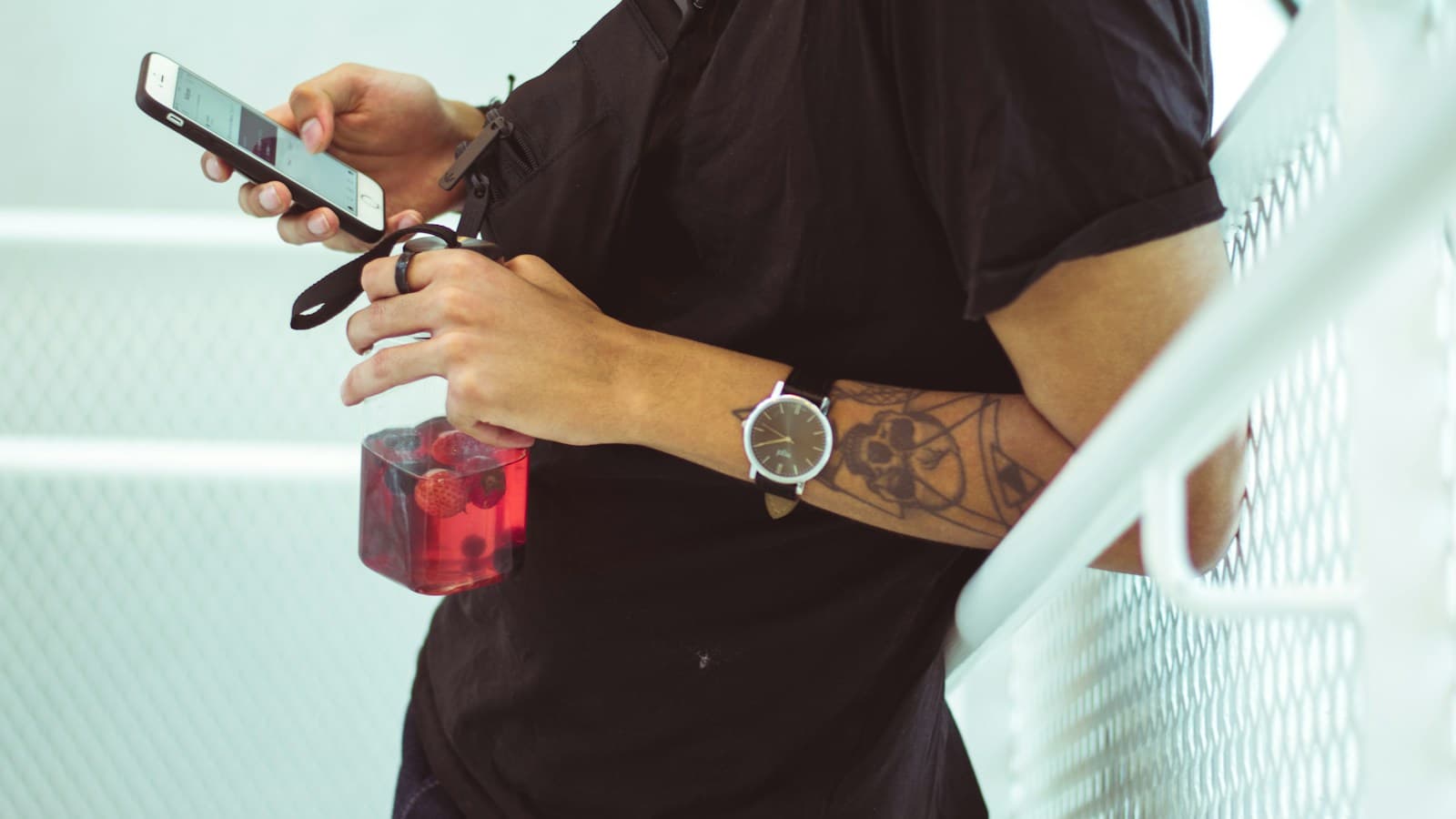 Barbeiro com tesoura e borrifador na mão confere uma mensagem no celular