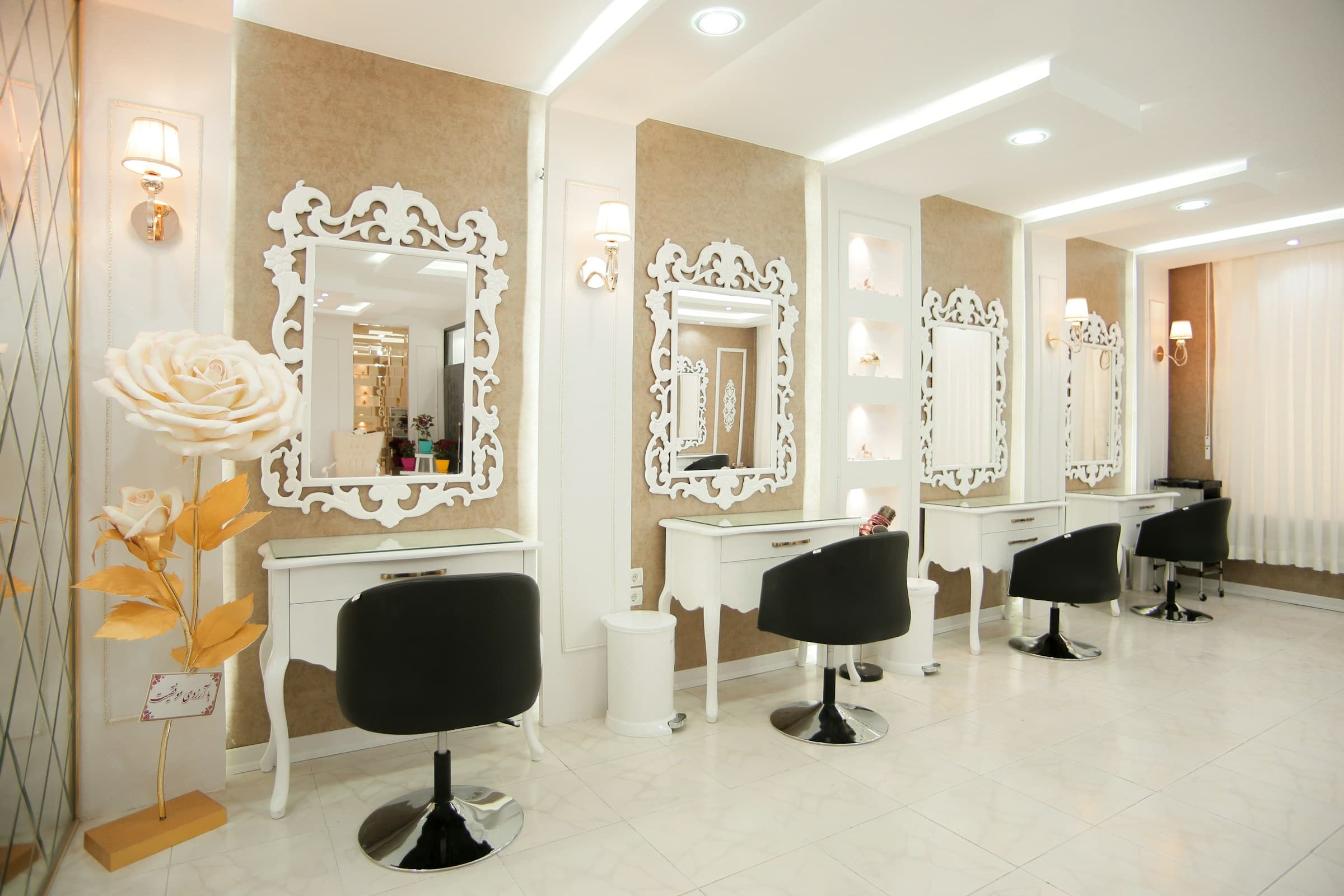 Salão de beleza com espelhos de moldura branca, cadeiras pretas e iluminação suave