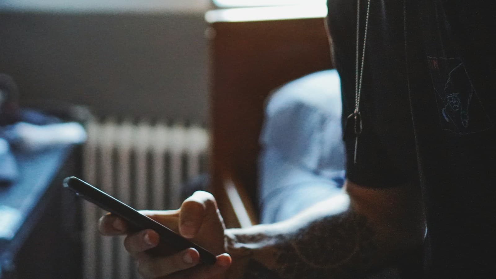 Barbeiro olha o celular enquanto o cliente espera na cadeira