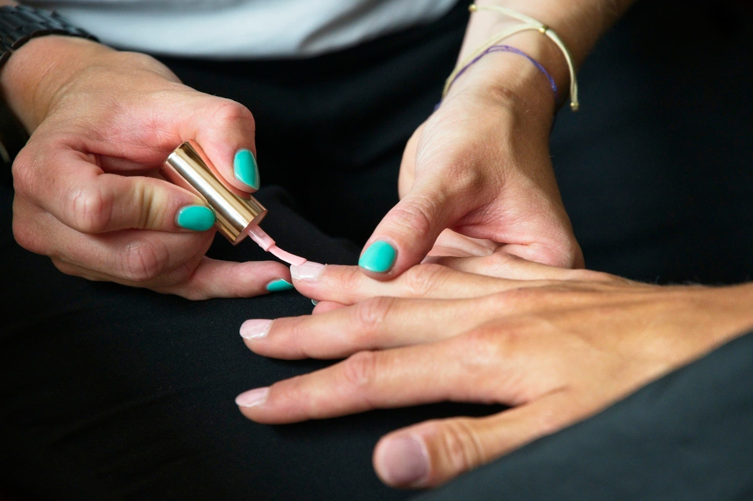Manicure pinta as unhas de uma cliente com esmalte em close