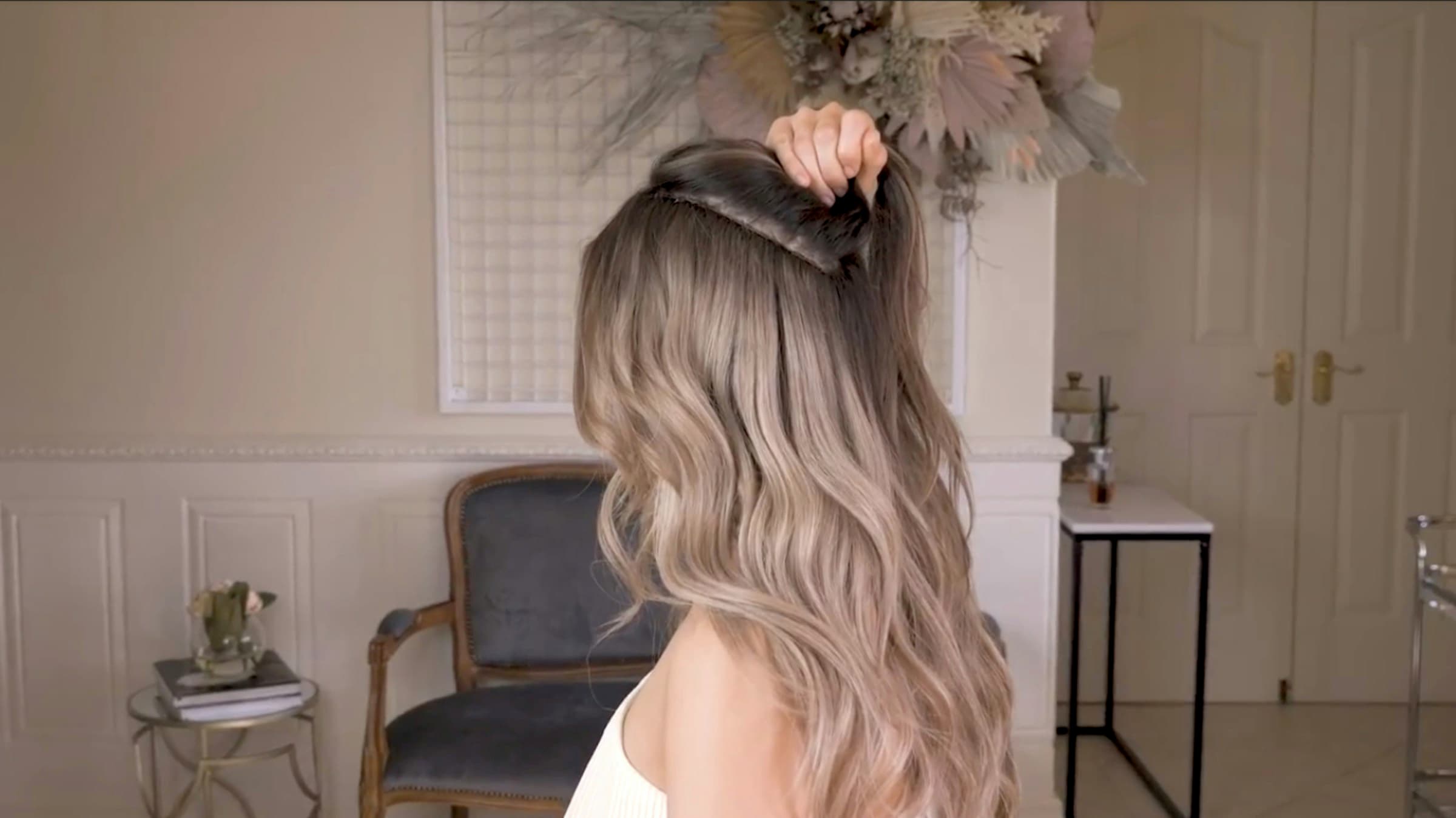 Mulher de costas com cabelo longo e ondulado em morena iluminada, do castanho na raiz ao loiro nas pontas