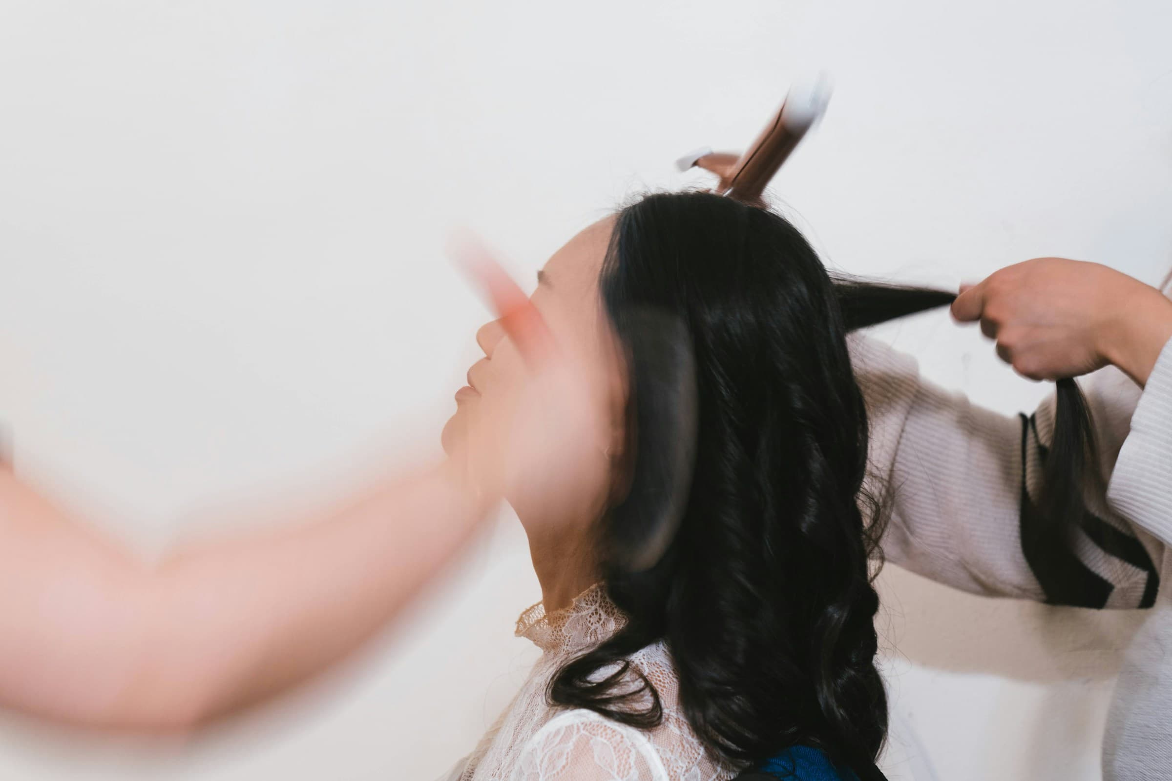 Cabeleireira corta e segura o cabelo longo e ondulado de uma cliente