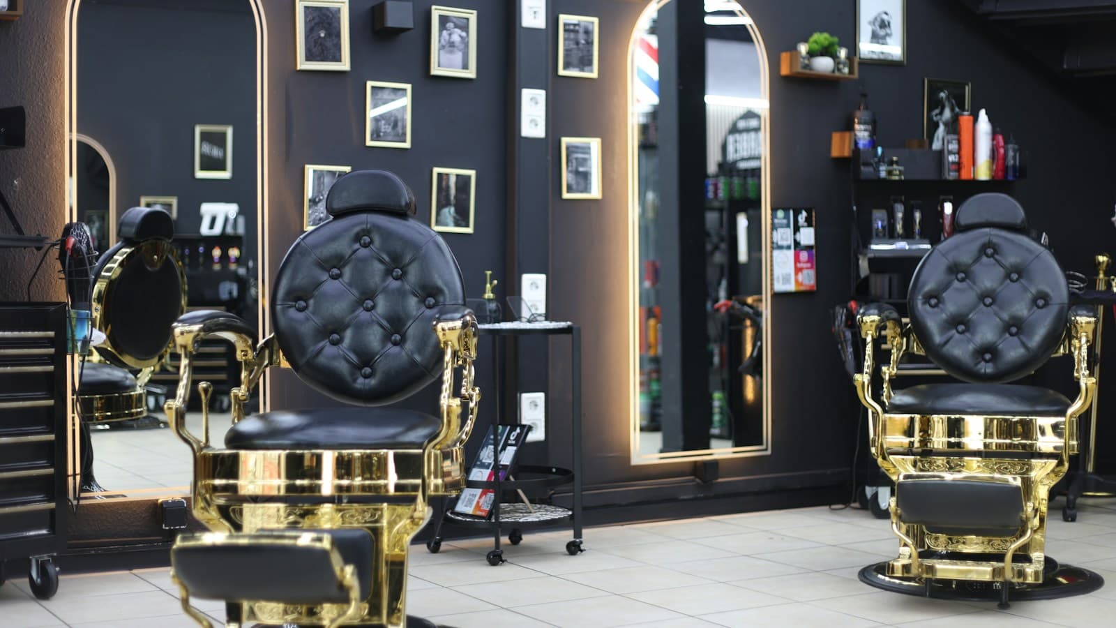 Cadeiras de barbeiro douradas e espelhos numa barbearia de paredes escuras