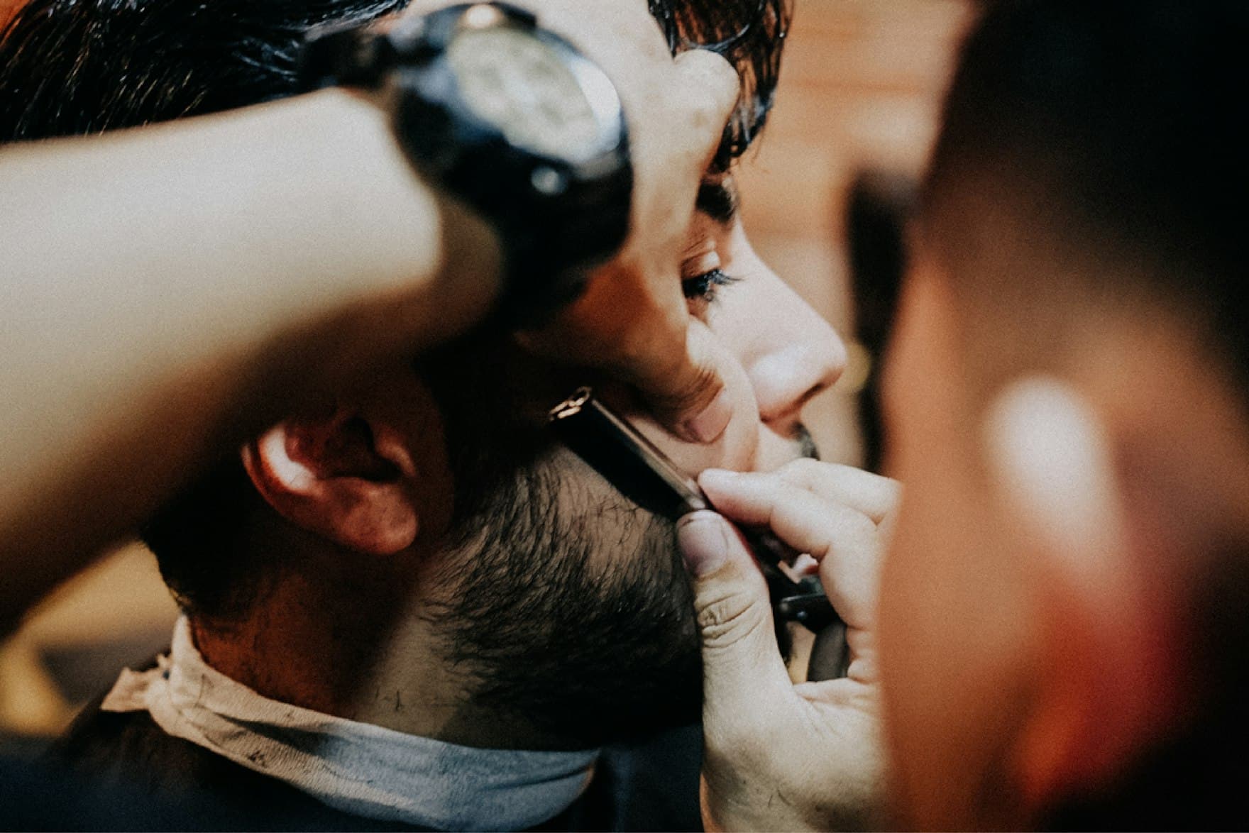 Barbeiro acertando a barba do cliente com a navalha